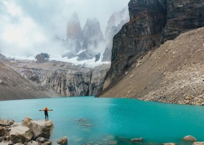 Hiker standing on rock overlooking turquoise lake at Torres del Paine Patagonia